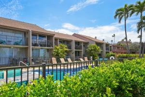 a pool at a resort with chairs and palm trees at Kihei Park Shores 13 in Kihei