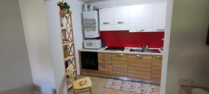 a kitchen with white cabinets and a red wall at Alessandro's Home in Carano