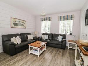 a living room with a black couch and a table at Nantucket Cottage - Part of the The Bay Filey Holiday Village with pool, gym and direct beach access, pub, restaurant, tennis and meadows walks in Filey +43 photos