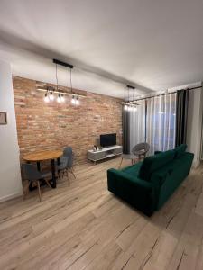 a living room with a green couch and a brick wall at Apartament WARSZAWA Kolejowa HUB EXPO in Warsaw