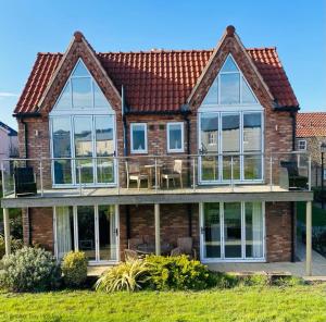 a house with large windows and a deck at Oyster Cottage in Filey