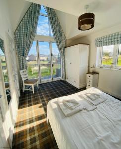 a bedroom with a bed and a chair and windows at Oyster Cottage in Filey
