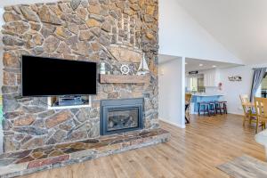 a living room with a stone fireplace with a flat screen tv at The Boat House Retreat in Lincoln City