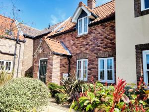 a brick house with a garden in front of it at Puddleduck Cottage - Part of the The Bay Filey Holiday Village with pool, gym and direct beach access, pub, restaurant, tennis and meadows walks in Filey