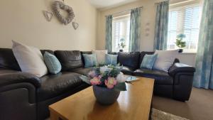 a living room with a couch and a table with a vase of flowers at Puddleduck Cottage - Part of the The Bay Filey Holiday Village with pool, gym and direct beach access, pub, restaurant, tennis and meadows walks in Filey