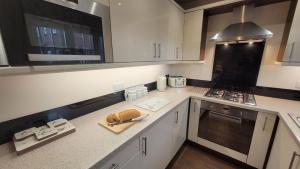 a kitchen with white cabinets and a stove top oven at Puddleduck Cottage - Part of the The Bay Filey Holiday Village with pool, gym and direct beach access, pub, restaurant, tennis and meadows walks in Filey +38 photos