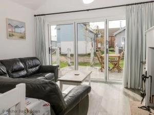 a living room with a leather couch and a sliding glass door at Sea-Renity - Part of the The Bay Filey Holiday Village with pool, gym and direct beach access, pub, restaurant, tennis and meadows walks in Filey