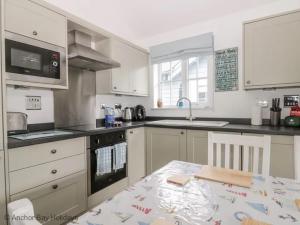 a kitchen with white cabinets and a table in it at Sea-Renity - Part of the The Bay Filey Holiday Village with pool, gym and direct beach access, pub, restaurant, tennis and meadows walks in Filey +44 photos