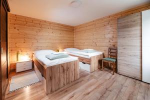 two beds in a room with wooden walls at Apartmán Florián in Martinske Hole