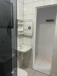 een kleine badkamer met een wastafel en een douche bij Suítes Lesther in Ubatuba