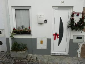 a white door with a red bow next to two windows at Casa Aguarela, estilo familiar na Serra da Estrela in São Romão