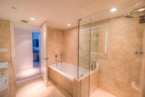 een badkamer met een bad en een glazen douche bij Oceanview Private Condo at 1 Hotel & Homes -1211 in Miami Beach