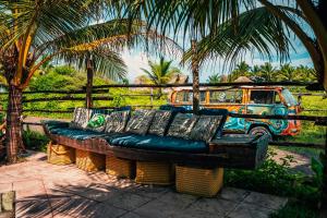 um sofá sentado em frente a uma carrinha com palmeiras em The Driftwood Surfer Beachfront Hostel / Restaurant / Bar, El Paredon em El Paredón Buena Vista