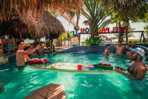 a group of men in a swimming pool with a surfboard at The Driftwood Surfer Beachfront Hostel / Restaurant / Bar, El Paredon in El Paredón Buena Vista