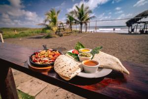 um prato de comida numa mesa na praia em The Driftwood Surfer Beachfront Hostel / Restaurant / Bar, El Paredon em El Paredón Buena Vista