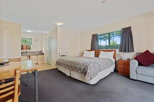 una camera con letto, scrivania e divano di Denton Park Motel a Christchurch