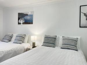 Cette chambre comprend 2 lits avec des draps et des oreillers blancs. dans l'établissement Pupuke Manor Motel, à Auckland