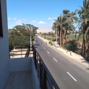 a road with palm trees on the side of a building at Habou City Apartment in Luxor