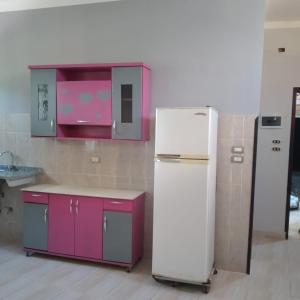 a kitchen with a white refrigerator and purple cabinets at Habou City Apartment in Luxor