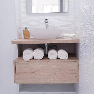 a bathroom with a sink and towels on a shelf at ENZO SUITE in Las Palmas de Gran Canaria