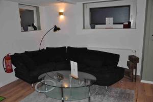 - un salon avec un canapé noir et une table en verre dans l'établissement Stadtnaher heller Souterrain, à Oldenbourg
