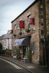 un edificio de ladrillo con una mesa y una sombrilla en Laburnum Guest House at Bistro En Glaze, en Wylam