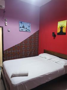 a bedroom with a white bed with a red wall at HOTEL BADINCA Alojamento Low Cost in Bissau avenida FRANCISCO MENDES in Bissau