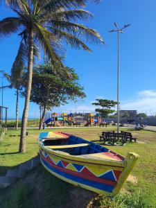 a boat sitting on the grass next to a palm tree at Casa Vista do Mar, praia e piscina in Vila Velha