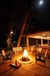 eine Feuerstelle mit Stühlen und Tischen in der Nacht in der Unterkunft Tuli Tiger Resort in Dhanwār