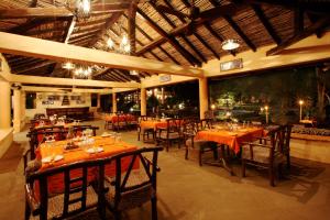 Tuli Tiger Resort في Dhanwār: مطعم بطاولات وكراسي في مبنى