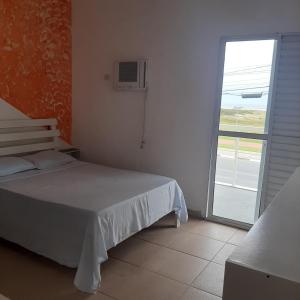 a bedroom with a bed and a sliding glass door at Pousada Aconchego in Ilha Comprida