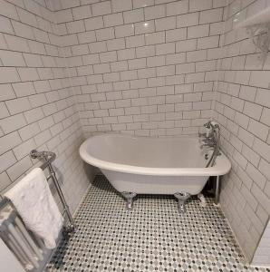 a bath tub in a white tiled bathroom at Lovely 1 Bed house in Largs, North Ayrshire in Largs