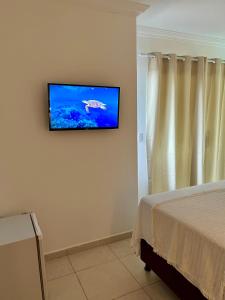 TV de pantalla plana colgada en la pared de un dormitorio en Maré Suítes Maragogi, en Maragogi