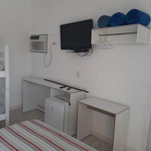 a white room with a desk with a tv and a computer at Pousada Aconchego in Ilha Comprida