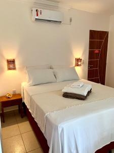1 dormitorio con 1 cama con sábanas blancas y ventilador en Maré Suítes Maragogi, en Maragogi