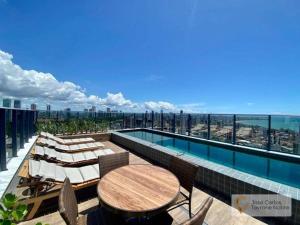 einen Balkon mit einem Tisch, Stühlen und einem Pool in der Unterkunft One way in João Pessoa