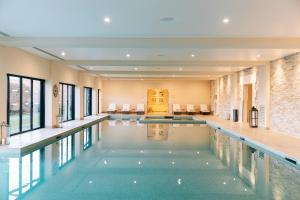 einen Pool in einem Haus mit Fenstern und einem Innenpool in der Unterkunft Hôtel Chais Monnet & Spa in Cognac