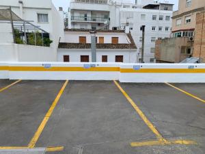 a parking lot with a white and yellow wall at Apartamentos Central B in Algeciras