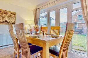 a dining room with a wooden table and chairs at Secluded 4 Bed Detached House with Driveway in Rainham