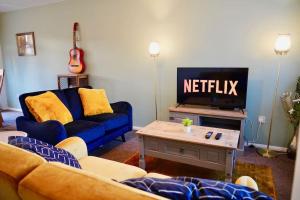 un salon avec un canapé bleu et une télévision dans l'établissement Secluded 4 Bed Detached House with Driveway, à Rainham