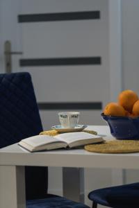 a table with a book and a bowl of oranges at Apartament Pod Jedynką in Bielsko-Biała