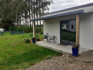 een huis met een patio met een tafel en stoelen bij Pin Oaks in Whanganui