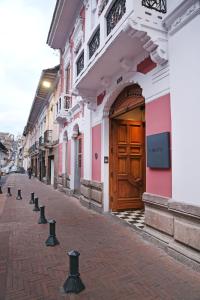 a street with pink and white buildings and a wooden door at Carlota Sustainable Design Hotel in Quito