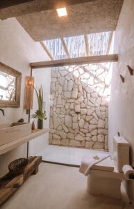 uma casa de banho com uma parede de pedra e um lavatório em Zai Patacho em Porto de Pedras