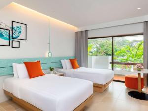 two beds in a room with a window at Novotel Rayong Rim Pae Resort in Klaeng