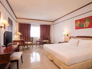 um quarto de hotel com uma cama grande e uma secretária em Mercure Chiang Mai em Chiang Mai
