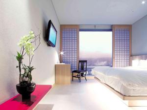 1 dormitorio con 1 cama y TV en la pared en Grand Mercure Ambassador Changwon, en Changwon