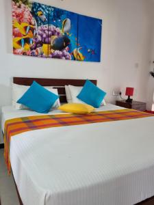 Wellé Wadiya Beach Villa في كالبيتيا: غرفة نوم بسرير ابيض ومخدات زرقاء وصفراء