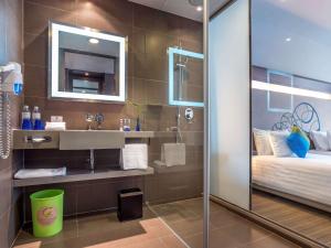 a bathroom with a shower and a sink and a bed at Novotel Bangkok Ploenchit Sukhumvit in Bangkok
