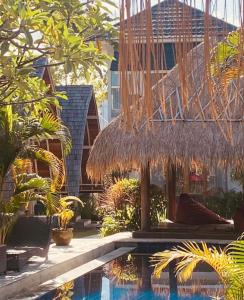 a resort with a swimming pool and a straw umbrella at The Hideaway Canggu in Canggu